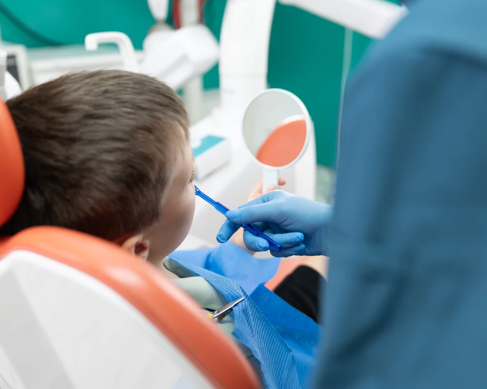 Dottore che mostra al bambino come lavarsi i denti