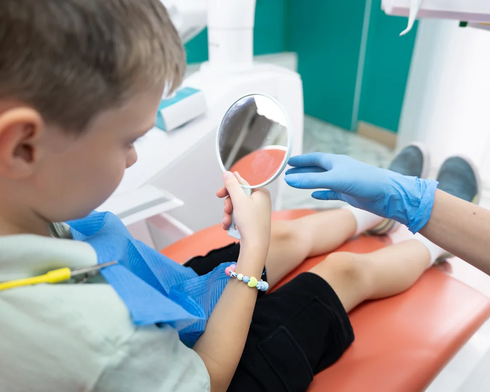 Bambino si specchia seduto in poltrona dal dentista